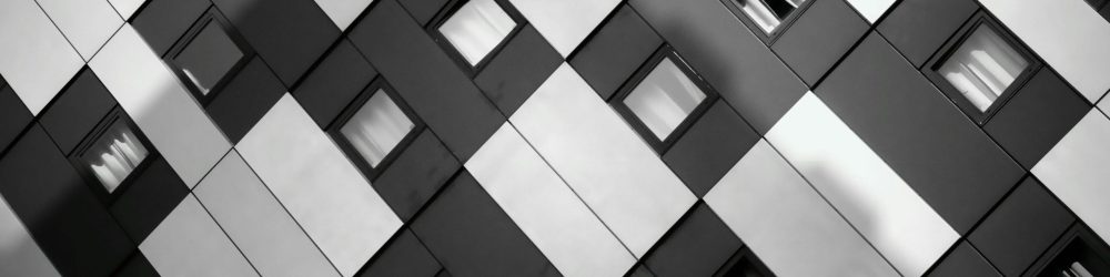 A striking monochrome image of a modern building's geometric facade with windows.